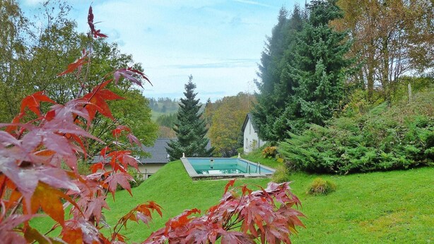 A pool surrounded by lush greenery and a house in the background. - Ferienhaus, Steinbach-Hallenberg (Steinbach-Hallenberg)