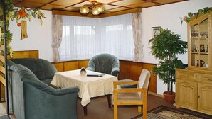 A room with a sofa, a chair, a small table, a cabinet, and a potted plant. - Ferienhaus, Steinbach-Hallenberg (Steinbach-Hallenberg)
