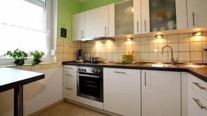 A kitchen with white cabinets, a black countertop, and a window with blinds. - Ferienhaus, Dornumersiel (Dornumersiel)