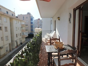 A balcony with a table, chairs, and a basket.
