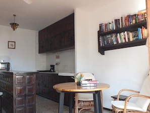 A kitchen with wooden cabinets, a coffee maker, and a bookshelf filled with books.