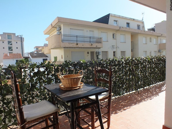 A balcony with a table, chairs, and a wicker basket.