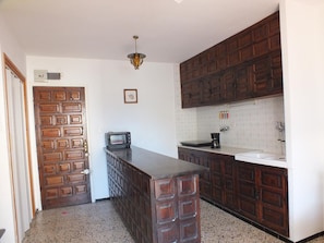 A kitchen with wooden cabinets, a countertop, a toaster, and a hanging light fixture.