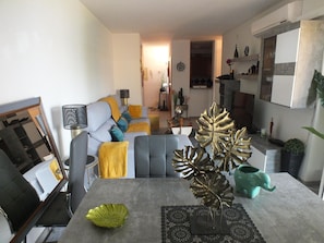 A modern living room with a grey sofa, a coffee table, and decorative leaves.