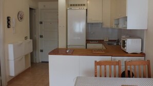 A compact kitchen with white cabinets, a microwave, and a small dining area with a table and chairs.