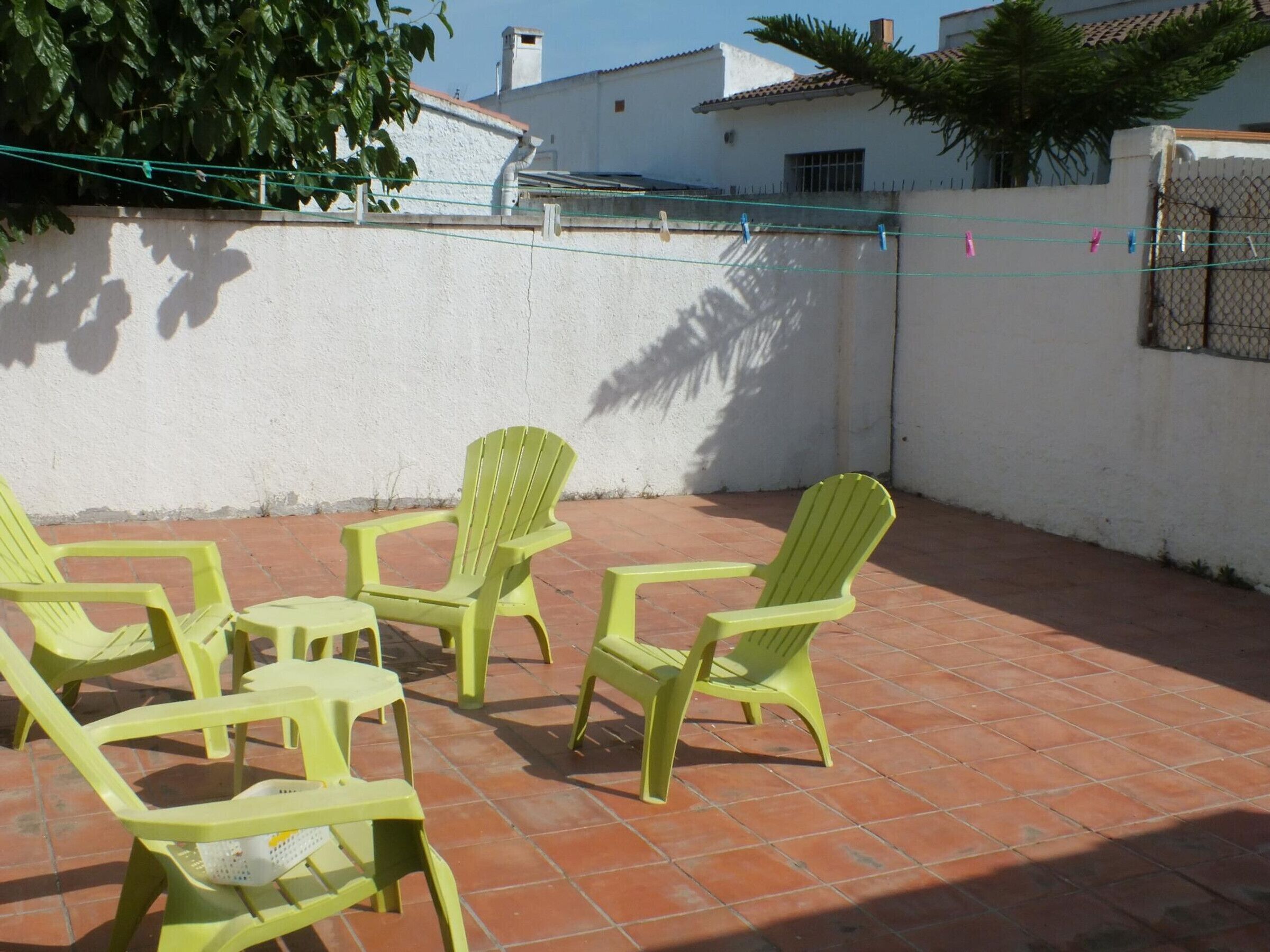 Een terras met vier groene plastic stoelen en een kleine tafel.
