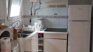 A compact kitchen with a sink, coffee maker, and a refrigerator.