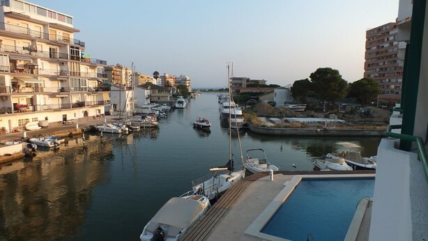 Un port de plaisance avec des bateaux amarrés, une piscine et des immeubles d’habitation en arrière-plan.