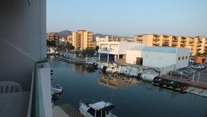 Un port de plaisance où sont amarrés plusieurs bateaux, entouré de bâtiments résidentiels et dominé par un paysage montagneux.