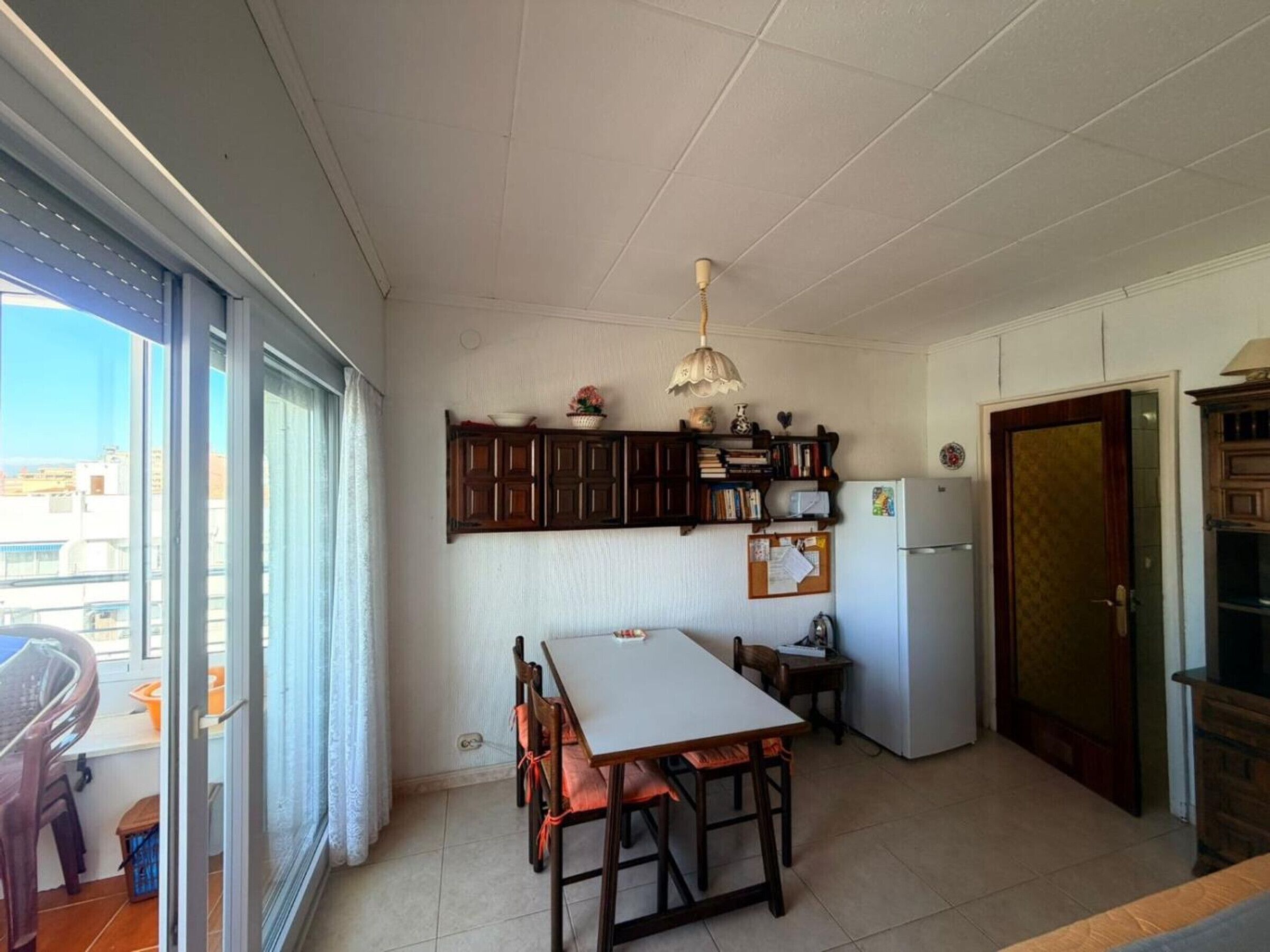 A kitchen with a dining table, chairs, a refrigerator, and a window with a view.