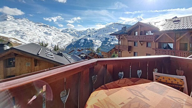 A mountain view with snow-covered peaks and a wooden building with balconies.