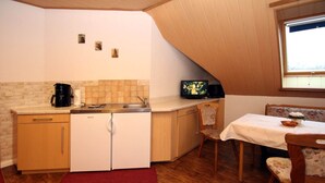 A compact kitchen with a refrigerator, coffee maker, and a small television.