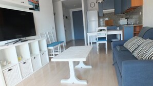 Una sala de estar con televisor, mesa de comedor y sofá.