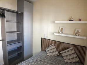 Ein Schlafzimmer mit Bett, Kleiderschrank und zwei Regalen mit Dekoration.