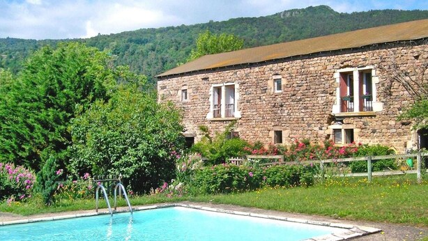 A stone building with a swimming pool, surrounded by lush greenery and a mountainous backdrop. - Rural Pool Retreat in the Hills (Retournac)