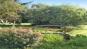 A garden with a wooden bridge, various plants, and trees. - Rural Pool Retreat in the Hills (Retournac)