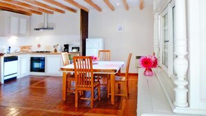 A spacious kitchen with wooden flooring, a dining table with chairs, and a refrigerator. - Rural Pool Retreat in the Hills (Retournac)
