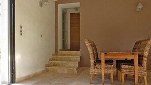 A dining area with a table and wicker chairs, a staircase, and a door leading to another room. - Relaxing Home Near Pool in Malaucène (Malaucène)