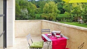 A balcony with a table set for two, chairs, and a yellow umbrella. - Relaxing Home Near Pool in Malaucène (Malaucène)