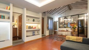 Un salon moderne avec un canapé, une table à manger et un coin cuisine visible à travers des portes vitrées.