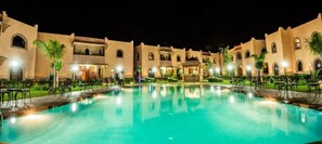 A pool area with a building in the background. - Appart Hotel Nzaha (Aghouatim)