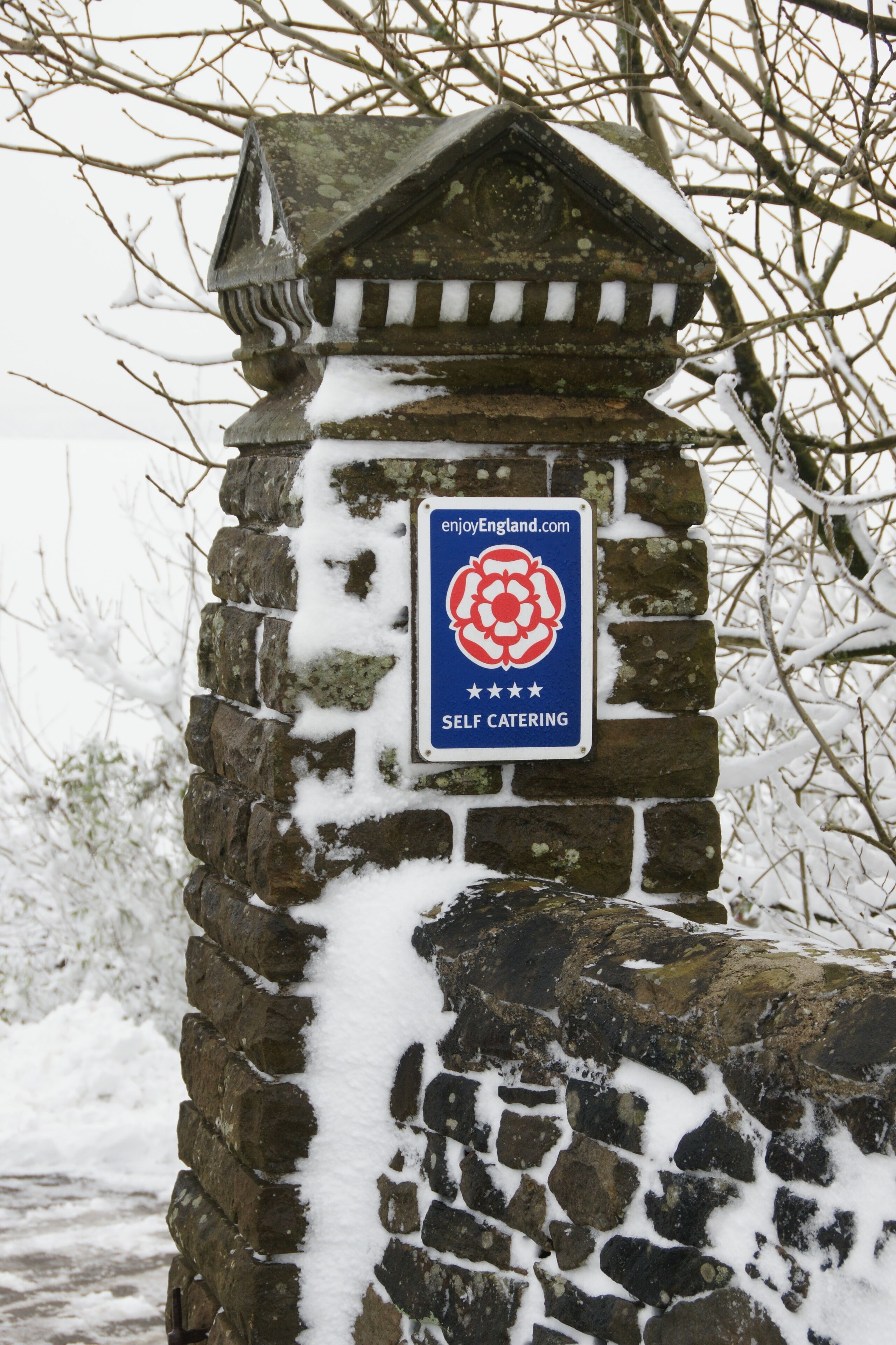 A stone wall with a sign indicating self-catering accommodation.