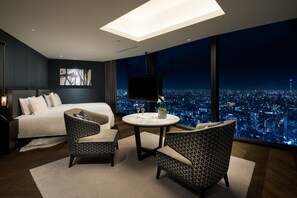 A modern hotel room with a large bed, two patterned armchairs, a round table, and a cityscape view through large windows. - BELLUSTAR TOKYO, A Pan Pacific Hotel (Tokyo)