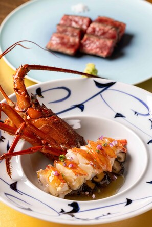 A lobster dish on a plate with a blue and white pattern, accompanied by a steak dish on a separate plate.