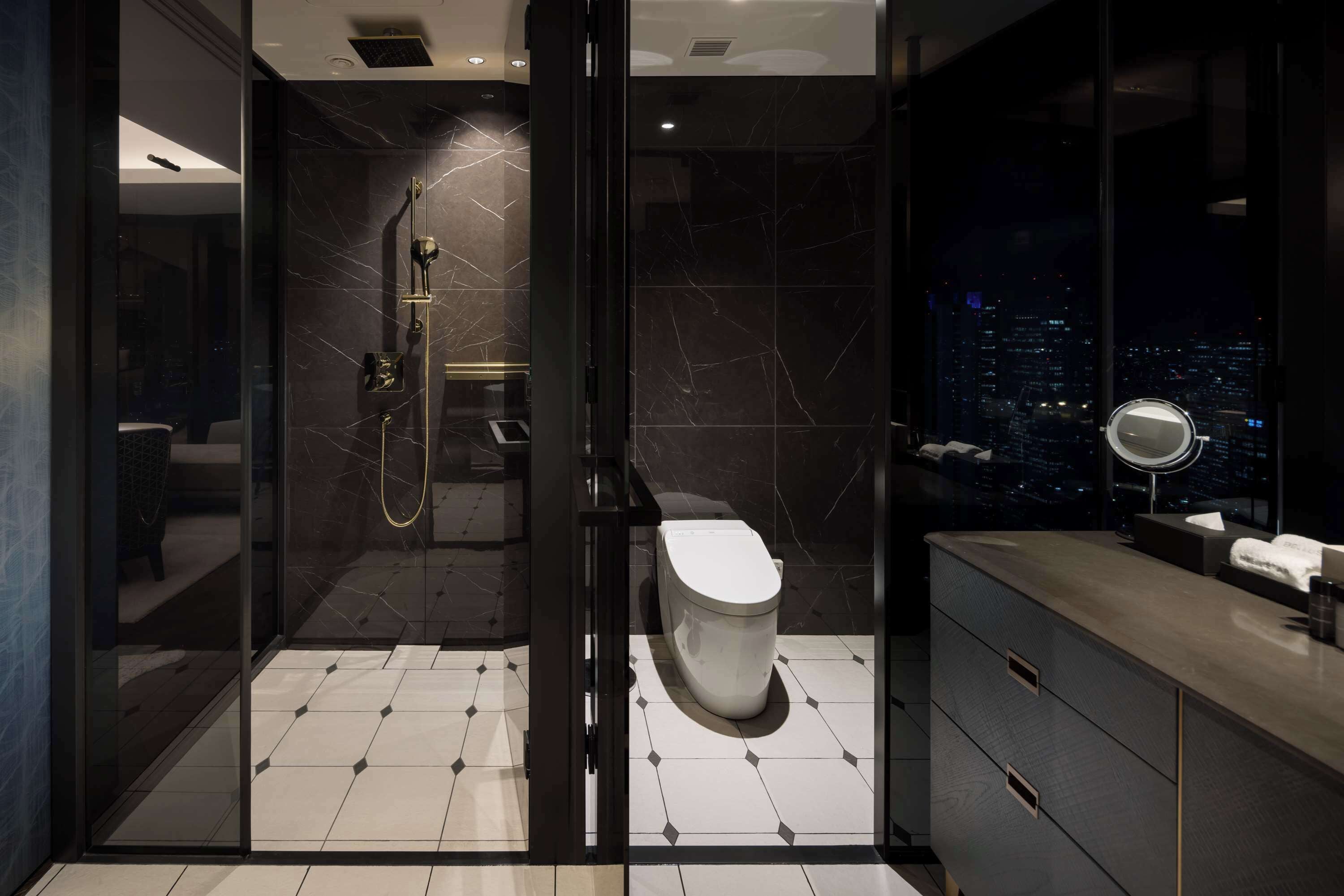 A modern bathroom with a glass-enclosed shower, a toilet, and a vanity with a mirror.