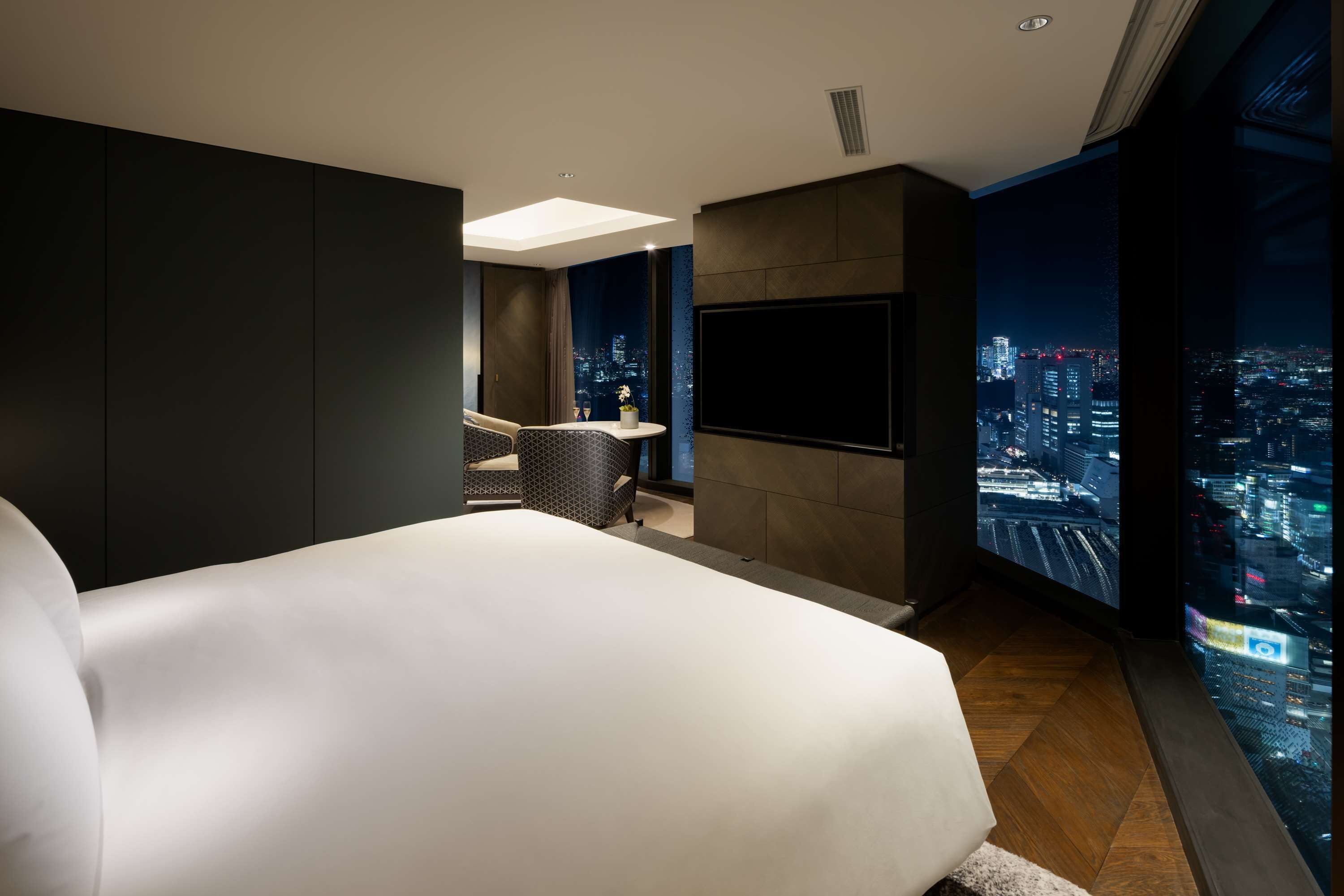 A modern hotel room with a large bed, a TV, and a city view.