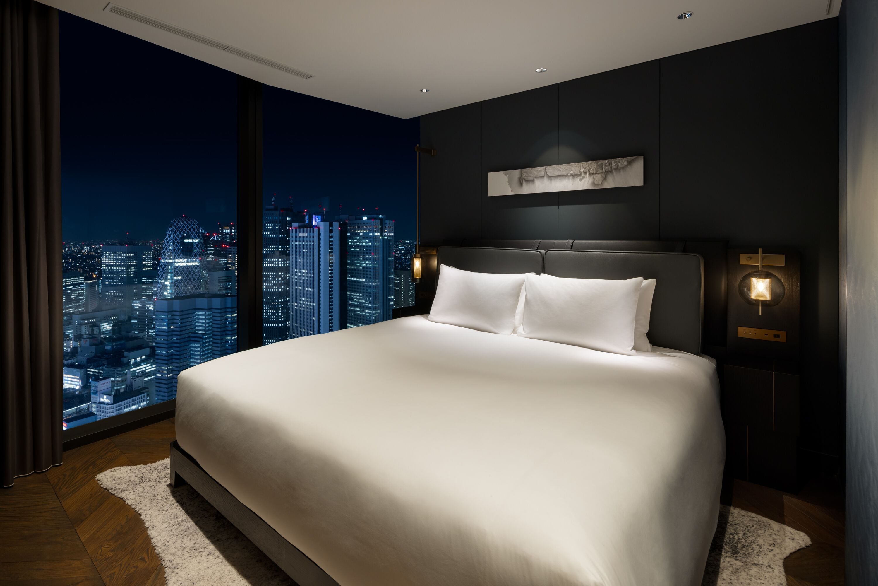 A modern hotel room with a large bed, city view, and contemporary decor.