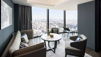 A modern living room with a city view, featuring a sofa, armchair, and round table with decorative items.
