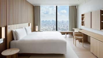 A modern hotel room with a large bed, a desk, and a view of the city.