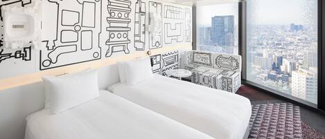 A hotel room with a large bed, a small sofa, a desk, and a city view.