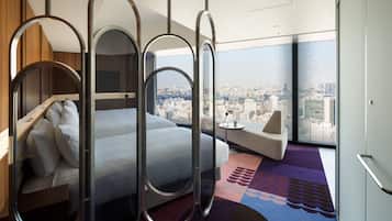 A modern hotel room with a bed, a sofa, and a city view.