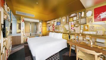 A hotel room with a large bed, a desk, and a chair. There is a shower area and a wall with various items displayed.