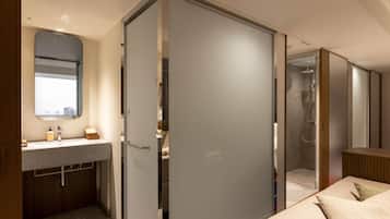 Een moderne hotelkamer met een badkamer, douche, bed en grote spiegel.