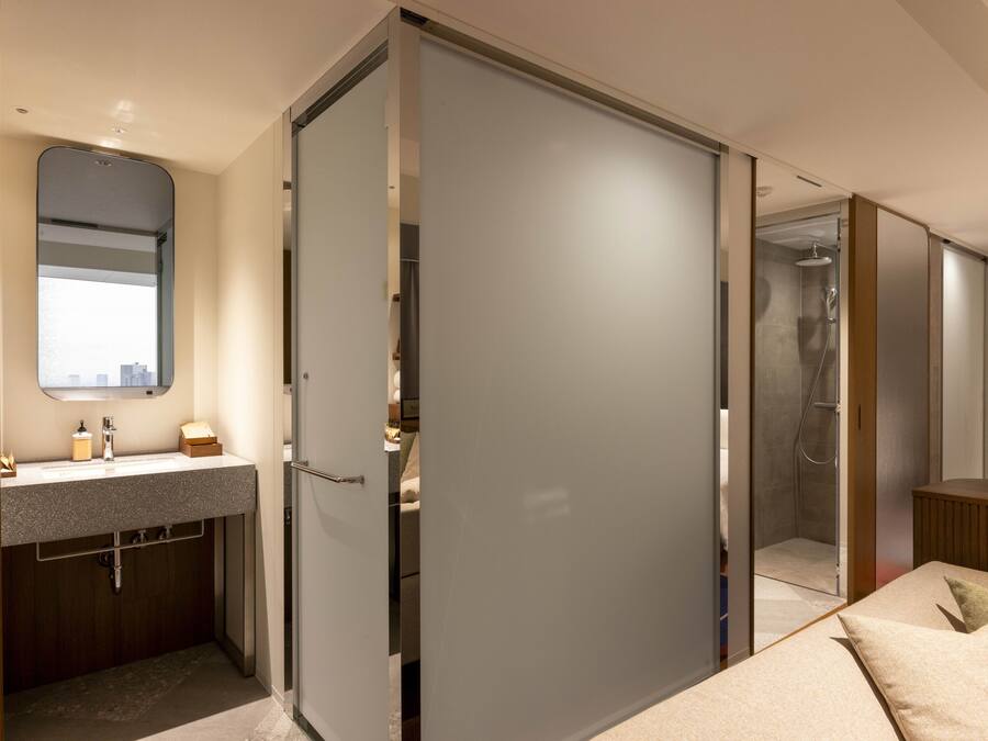 Een moderne hotelkamer met een badkamer, douche, bed en grote spiegel.