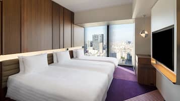 Une chambre d’hôtel avec deux lits, une grande fenêtre donnant sur la ville et un téléviseur à écran plat.