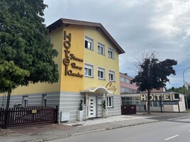 Un hotel con fachada amarilla, un letrero que dice "Hotel Zimmer Ross Chambers City" y un cartel direccional que indica "Einfahrt".
