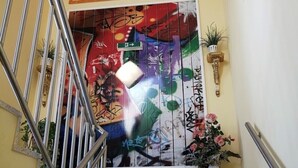 A staircase with metal railings, a wall with graffiti art, a potted plant, and a decorative vase.
