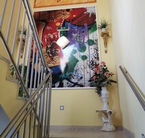 Uma escadaria com grades de metal, parede com arte de graffiti, uma planta em vaso e um vaso decorativo.