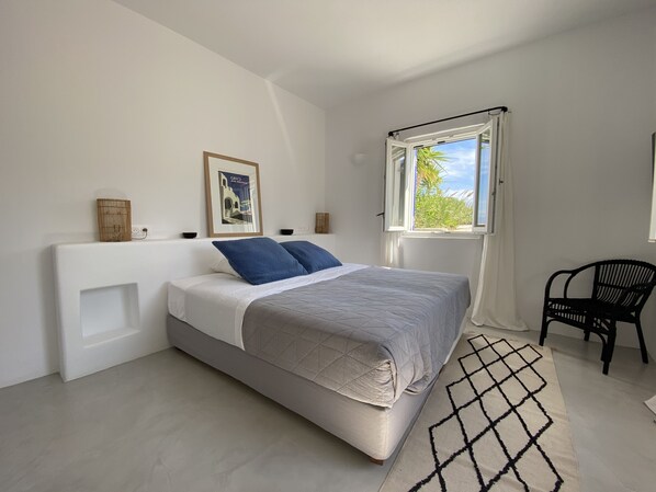 A bedroom with a bed, a window, a chair, and a picture on the wall. - NAOUSSA MAGIC SAE VIEW / 10 MINUTES WORK TO THE BAECH (Náoussa)