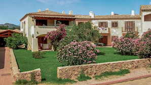 Un bâtiment à deux étages, doté d’un toit en tuiles, de murs en pierre et d’un jardin bien entretenu agrémenté d’arbustes en fleurs.