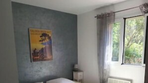 Una camera da letto con un letto, cuscini, un comodino, un quadro appeso e una finestra con tende.