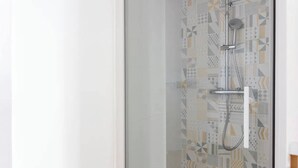 Eine Dusche mit Wandfliesen in geometrischem Muster.