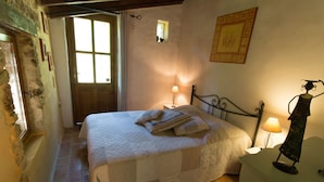 A bedroom with a large bed, two bedside lamps, a window, and a door.