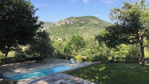 A hot tub and swimming pool in a backyard with a mountain view.