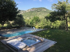 Relax in a serene hot tub surrounded by lush greenery and breathtaking mountain views.