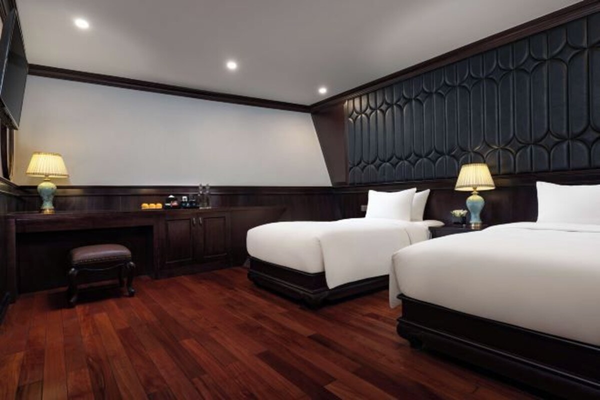A hotel room with two beds, a desk, and a chair.